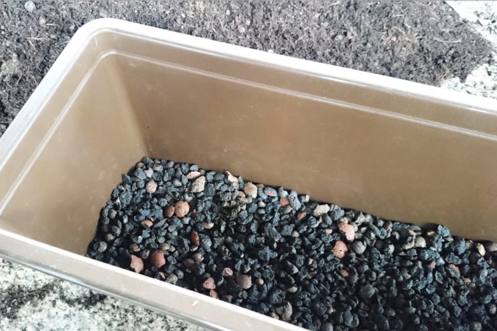 Blumenkasten vor dem Bepflanzen: Unten ist eine Drainageschicht aus gebrochenem Blähton eingefüllt.